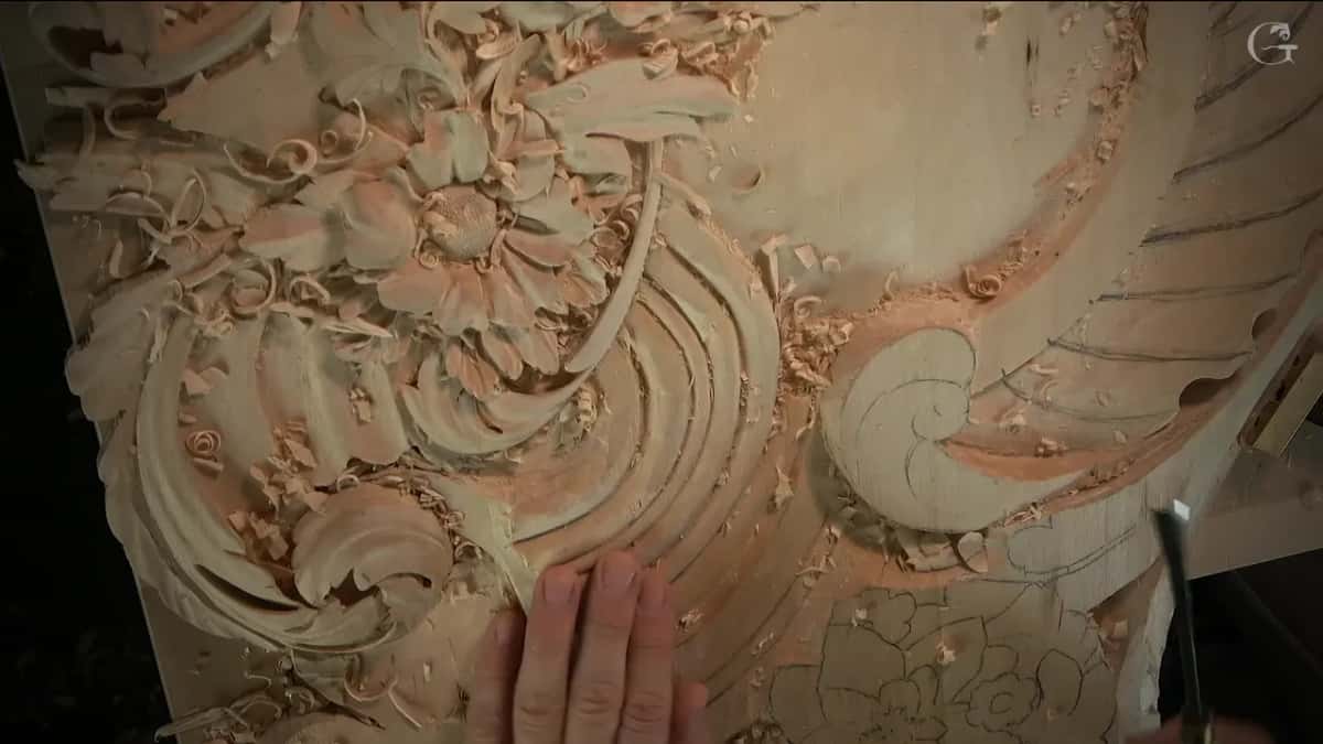 The run of curved bands seen from above with one hand laid flat on the panel and a gouge at the right