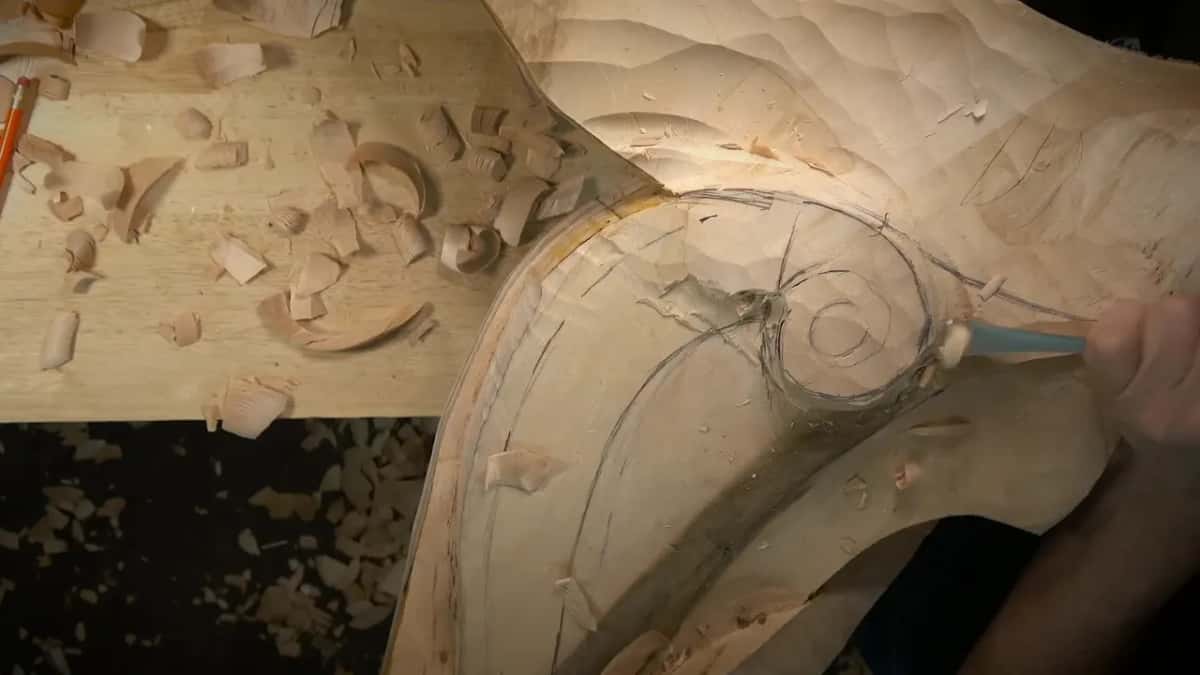 One hand guides a gouge along the slope next to the spiral
