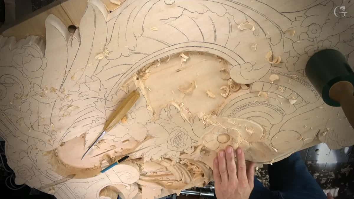 Panel seen from above, one gouge lying across the carving and a green mallet at the right