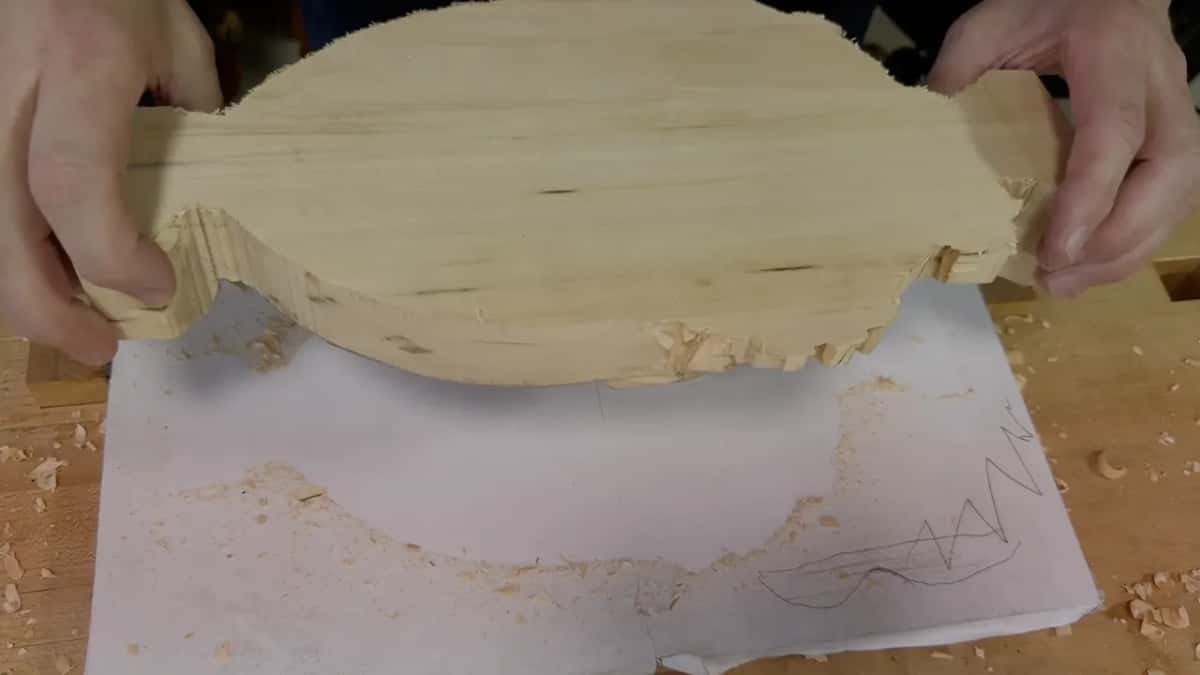 Tray coming off the board Both hands lifting a carved tray free of its board