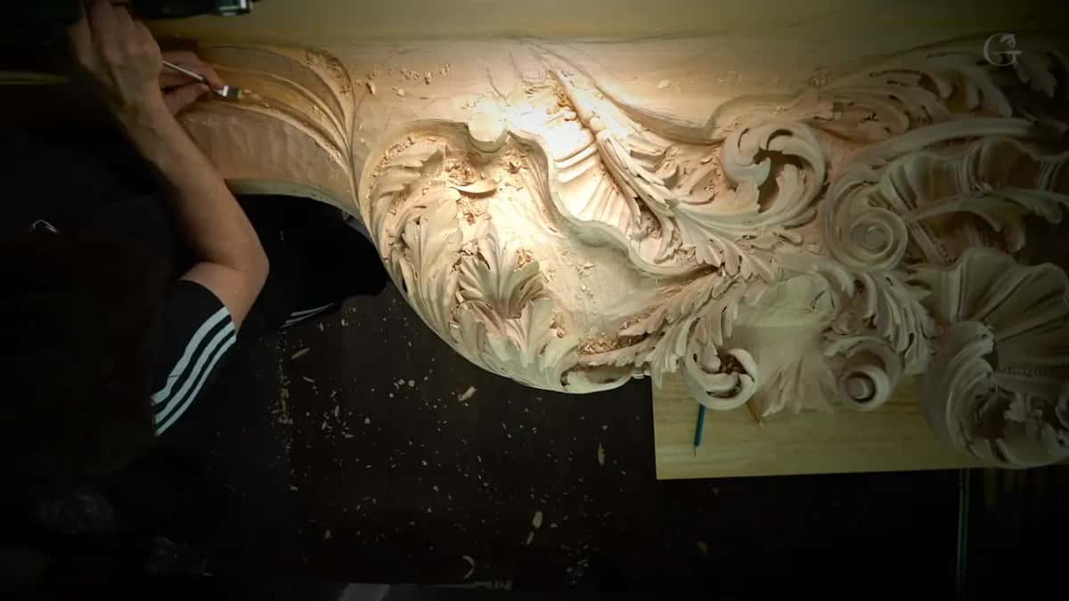 From above, an arm in a striped sleeve carves at the far left of the long panel while the rest waits in lamplight