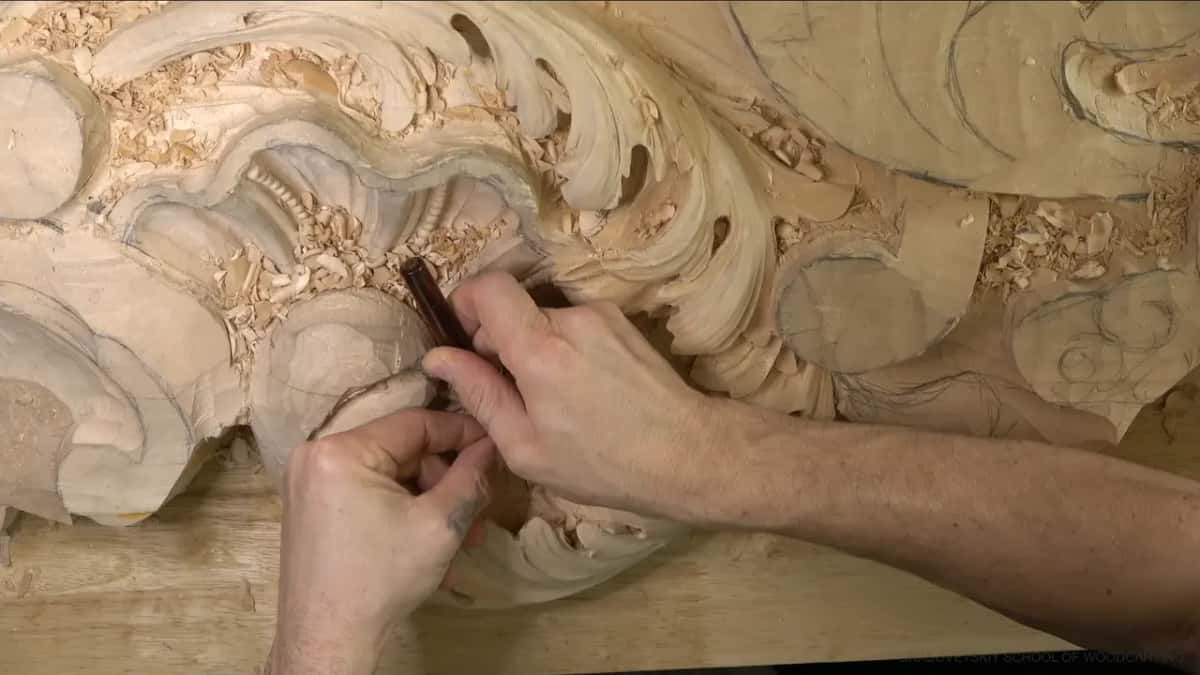 Both hands steady a small dark-handled tool against an edge near the center.