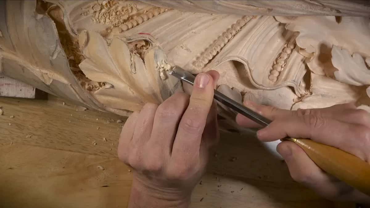 Both hands drive a long tool along the lower edge of the leaf
