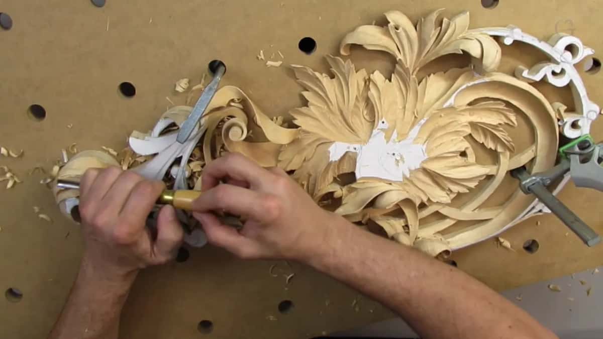 Both hands on one tool above the panel, with the whole design visible behind them and the board underneath.