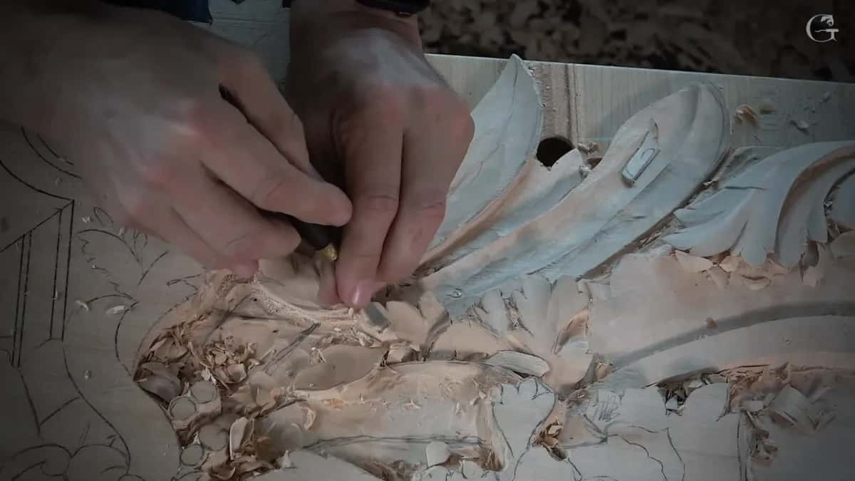 Both hands pinched close together around a very small tool near the base of one leaf