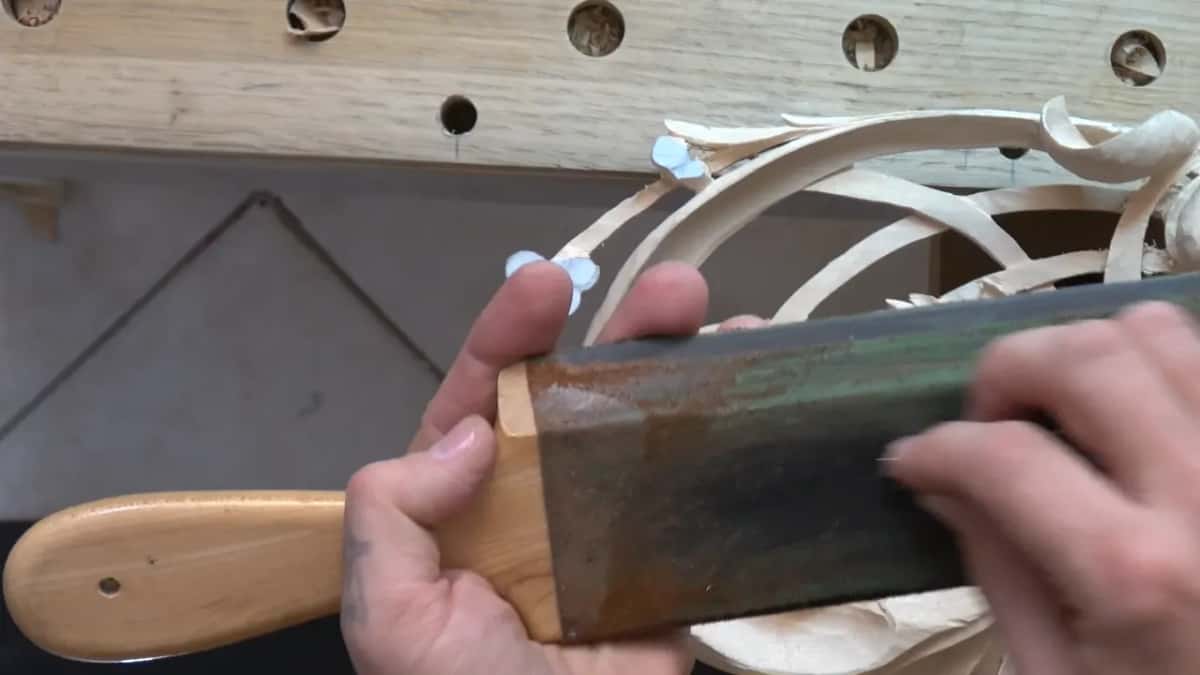 Both hands on a handled strop, its dark leather face toward the camera