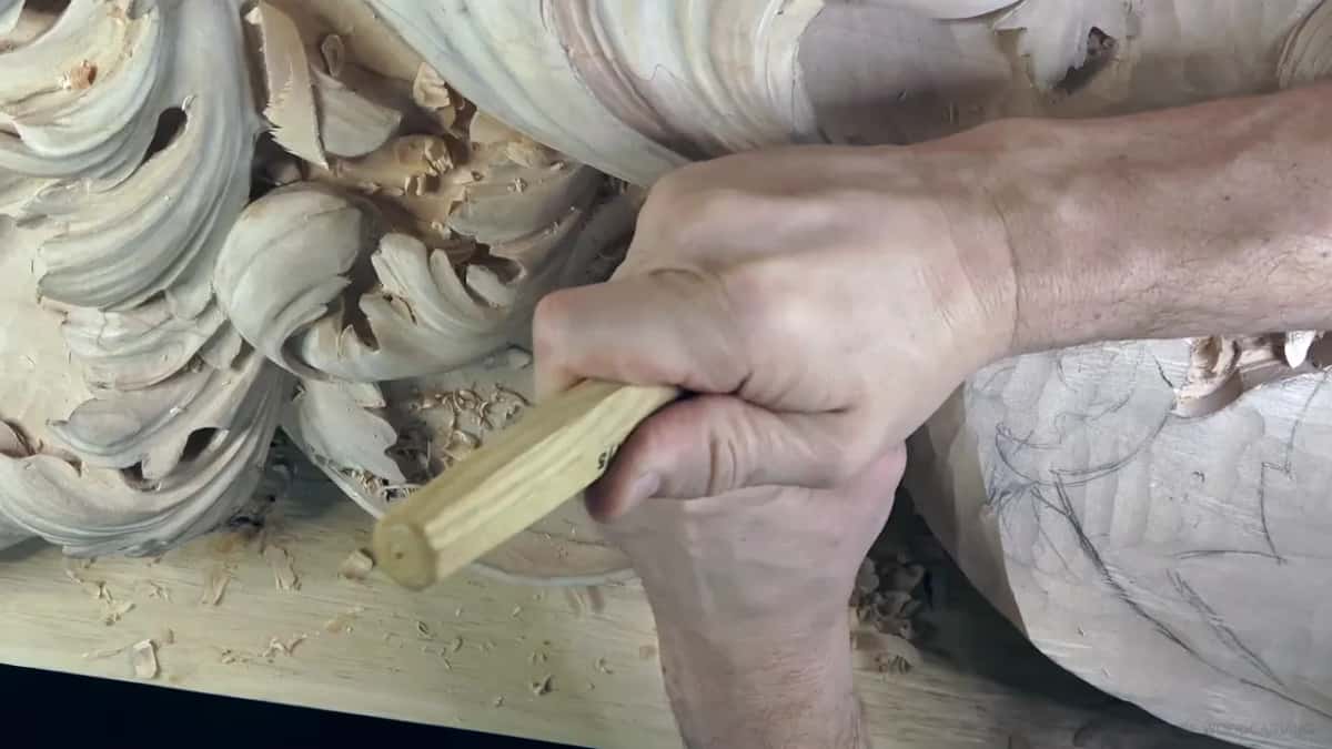 A fist wraps a light handle while pencil arcs cover the smooth wood beside a rolled leaf.