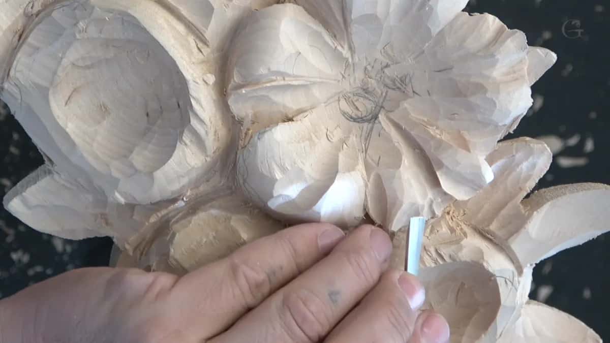 Fingers of both hands on the flower, a steel shank held upright against one petal