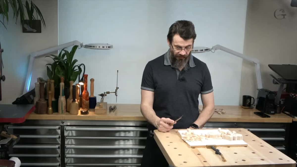 Standing at the table with a small tool, looking down at the panel