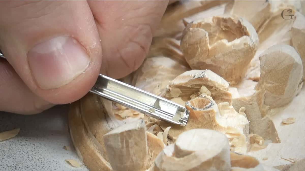Small gouge pinched between thumb and finger at the rim of the round center