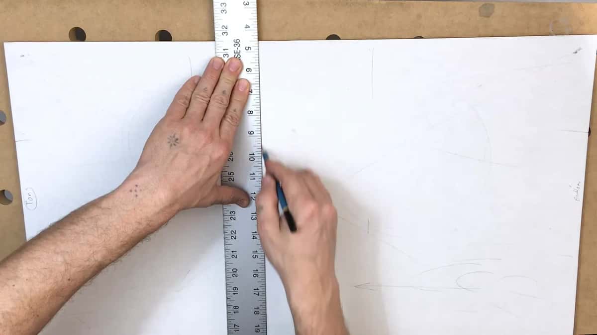 Steel rule stood down the paper while the other hand keeps a pencil ready at the mark