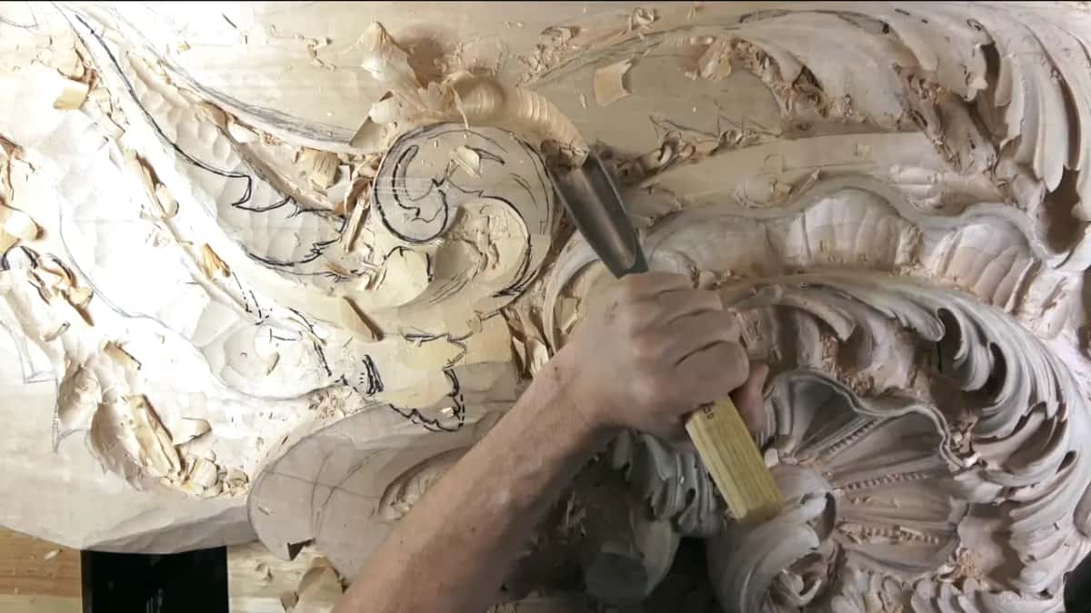 A gouge with a yellow handle works around the edge of the shell, next to lines drawn in marker.
