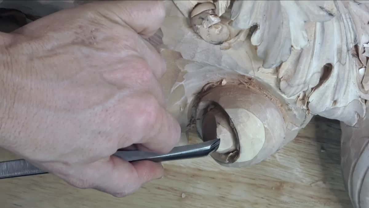 One large hand grips a long straight shank and sets its tip under the lower edge of the curl.