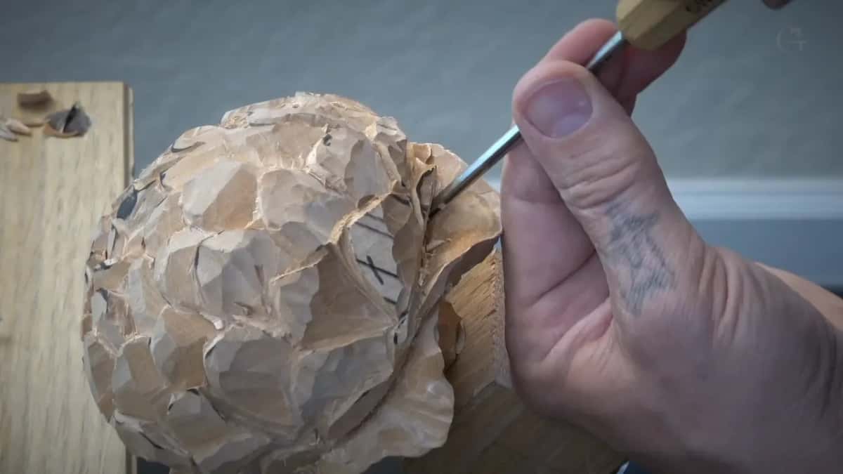 Thin tool meets the right side of the round flower, held in the fingertips, X marks beside it