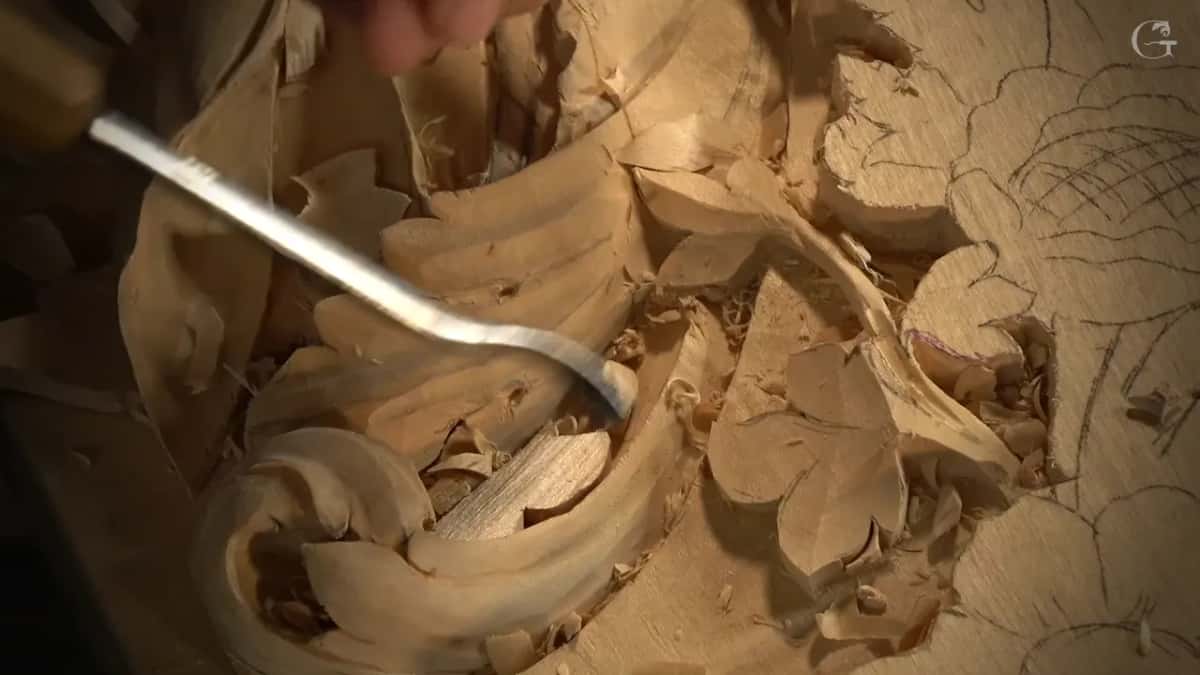 Bent tool curling down into the hollow of a scroll among loose chips.