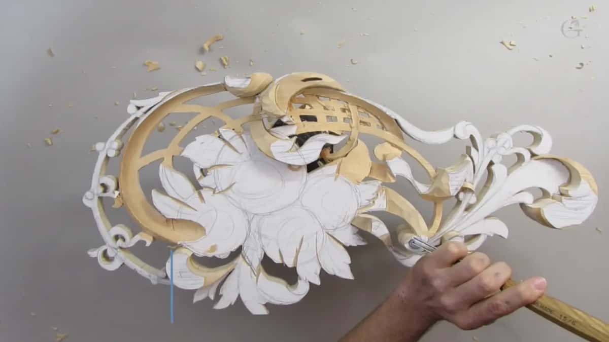 Panel from above, one hand pushing a long-handled tool into a curl near its lower edge