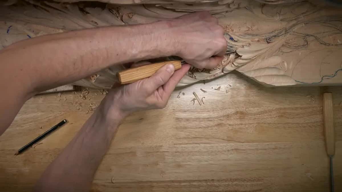Right hand wraps a short pale handle while the left hand guides the blade into the leaf