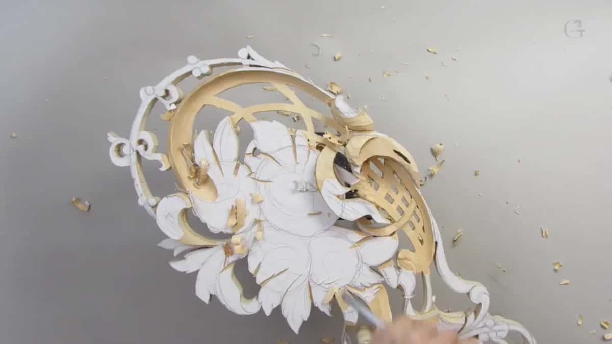 Top view of the pierced panel, white pattern paper still on the flowers and leaves, chips scattered on a grey surface