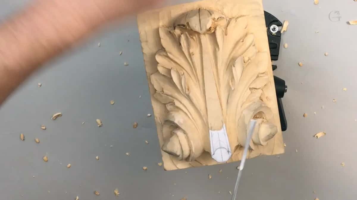 Panel upright on the vise, a hand blurred in motion, shavings everywhere on the gray table