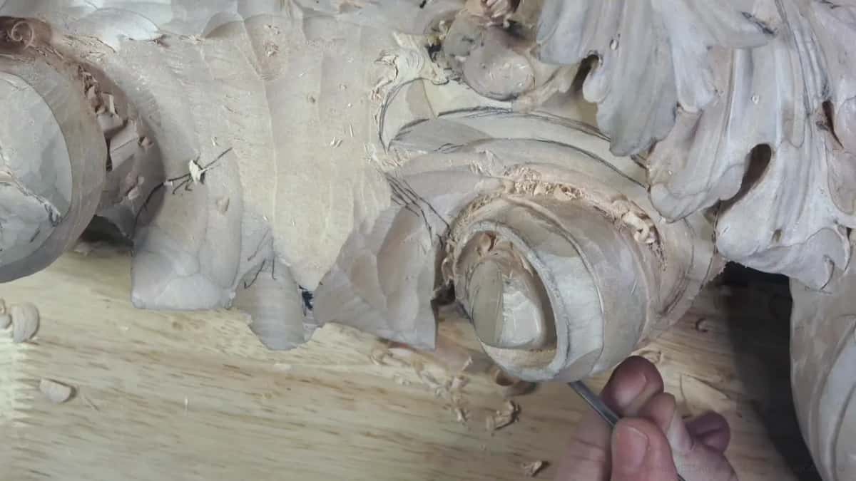 Pencil lines cover the flat wood beside the curl, seen from above.