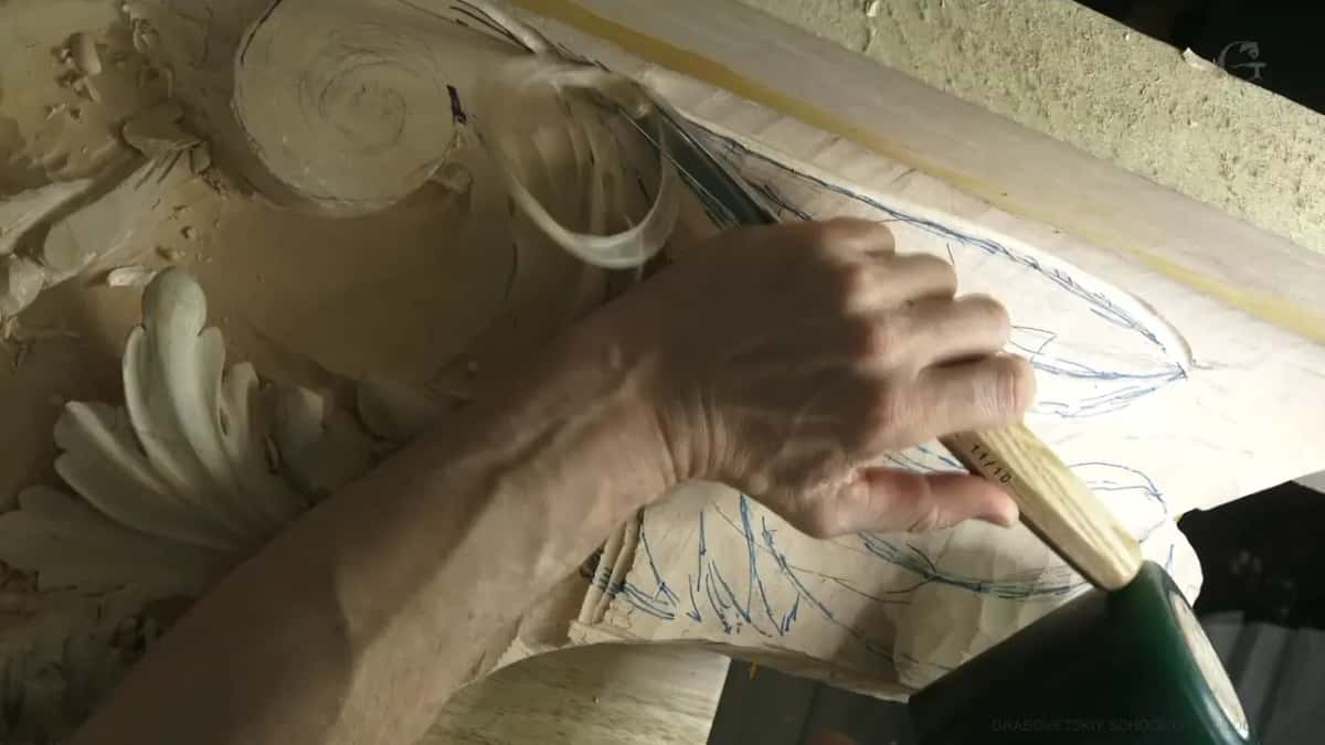 One hand sets a pale handle beside blue lines.
