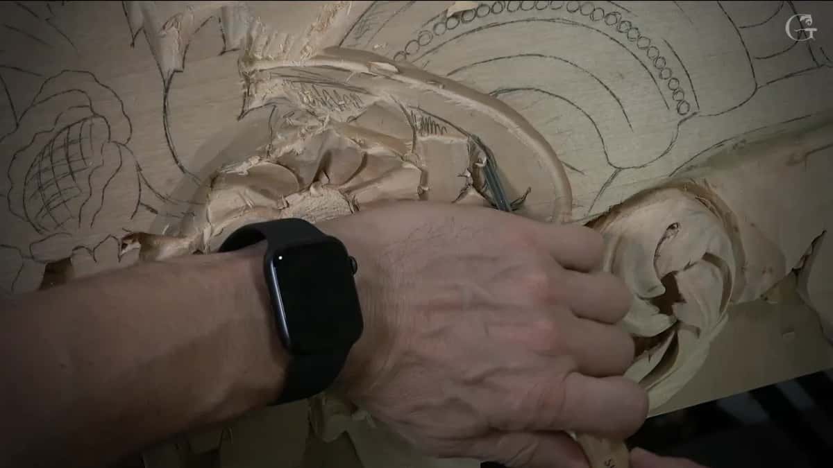 Hand with a smartwatch steering a slim veiner along the edge of a scroll, chips scattered over the flower beside it