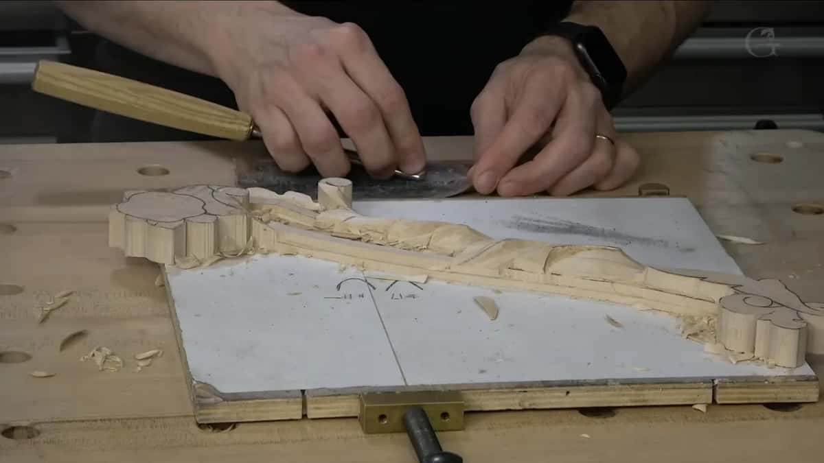 Yellow handle in hand, the blade drawn along a dark strip at the edge of the bench.