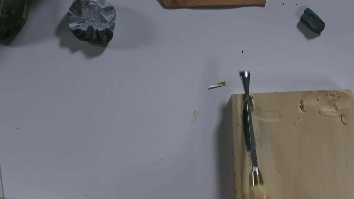 Gouge lying in a groove at the edge of the block, green compound inside.