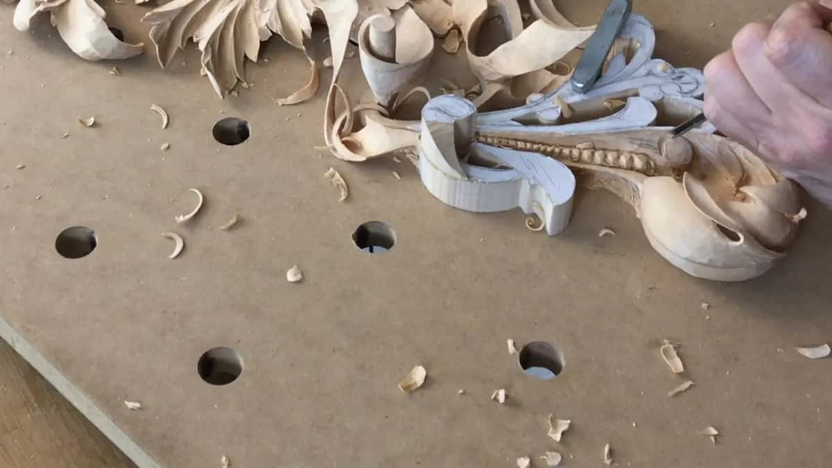 Chips lie scattered across the drilled board while a tool works in at the right end of the band