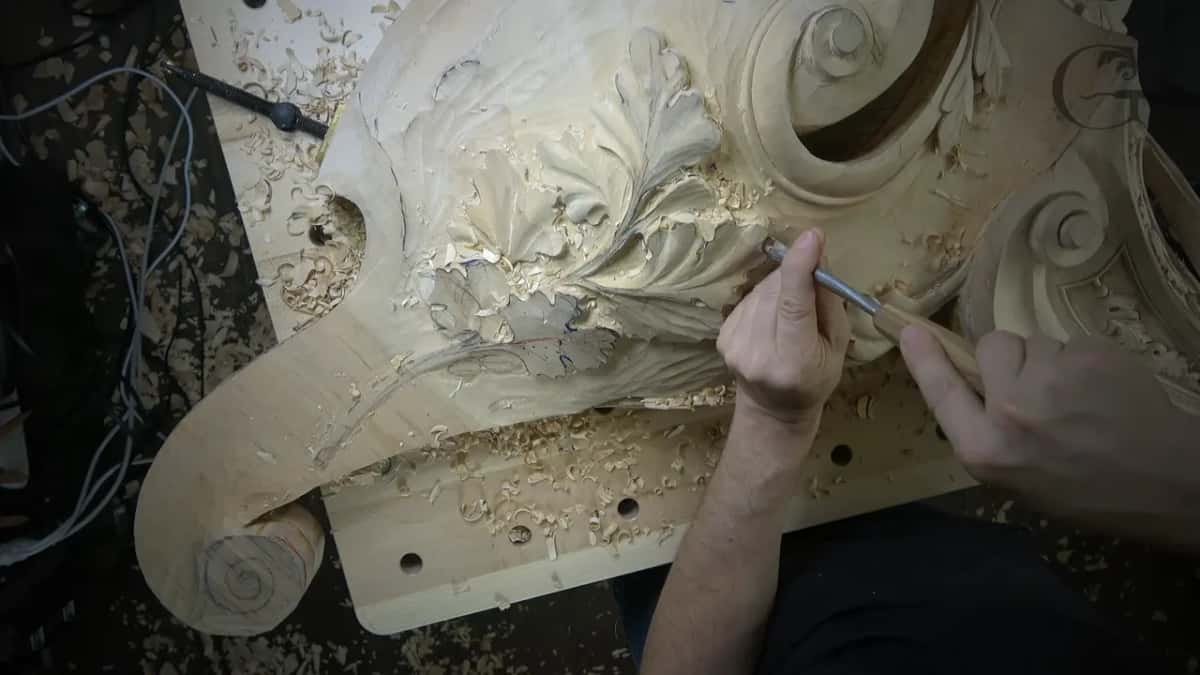 A scroll curls at left and at right while the gouge works between them.