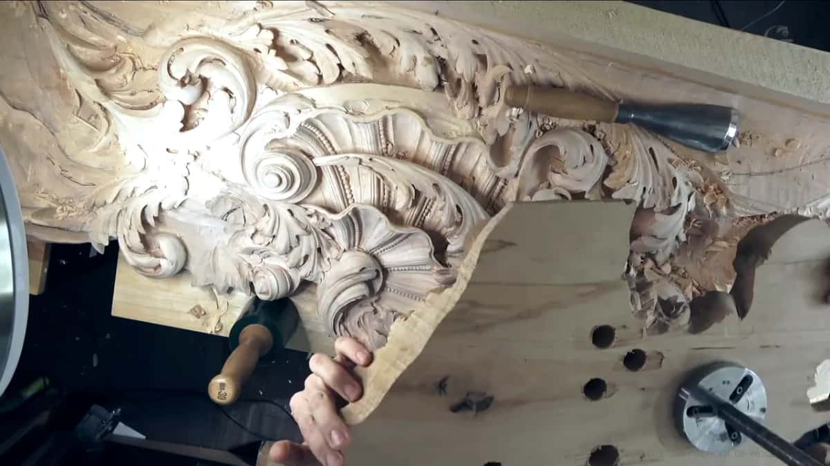 Plywood with drilled holes and a round steel plate, held up beside the carving and the green mallet.