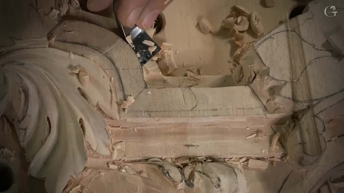 A gouge works down inside the hollow of the molding, loose chips piled along its edge