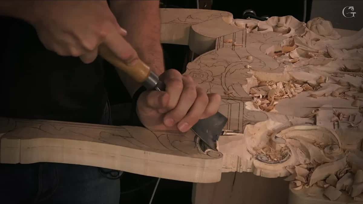 Seen from the side, both hands drive the wide blade along the edge