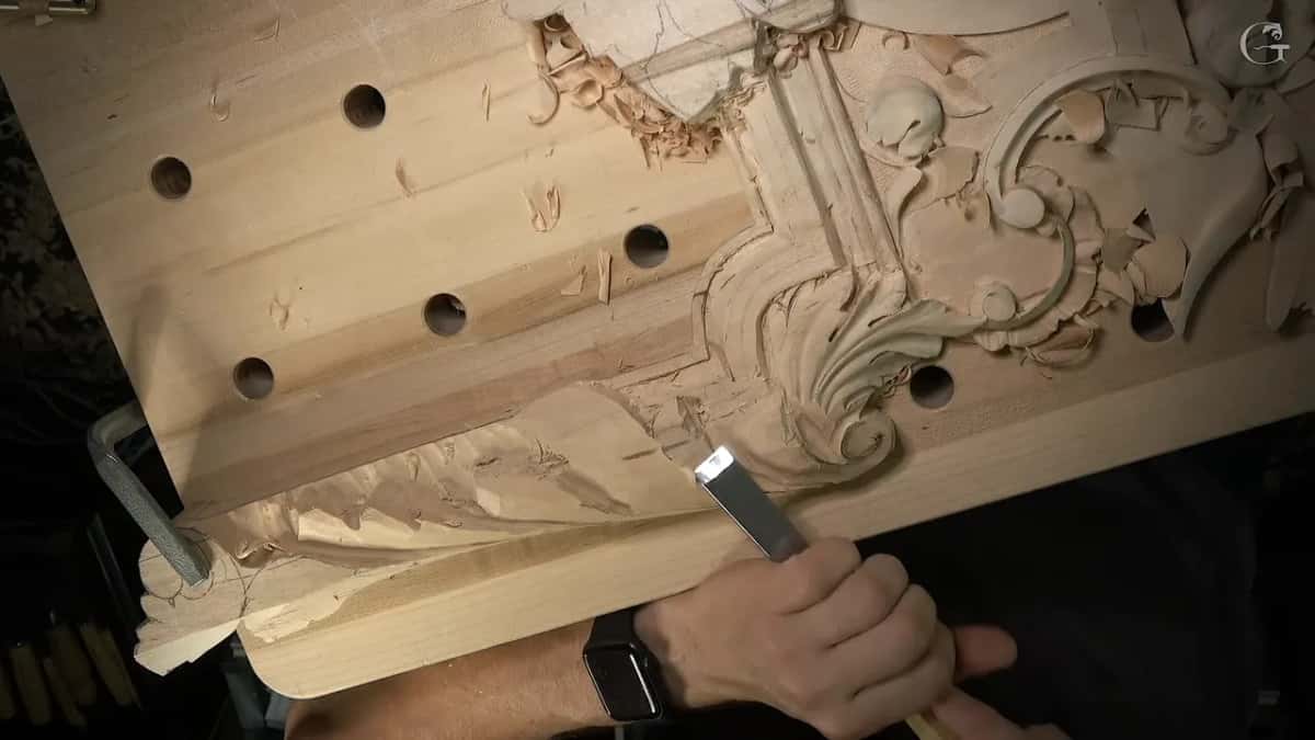 Flat gouge with a bright blade rolling the shape beside the acanthus