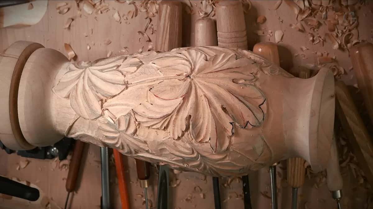 Seen from above, the carved basswood vase rests on its side with notched leaves and gouges lined up behind it