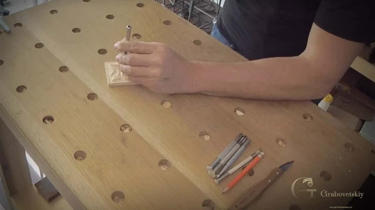 Wide view of the bench as a punch goes into the rosette, with more punches and a knife nearby