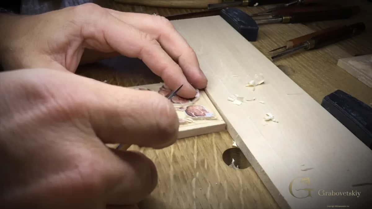 Wide view of two hands at work, the knife small between them.