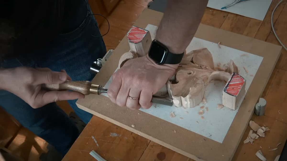 Board turned sideways, two hands on one gouge