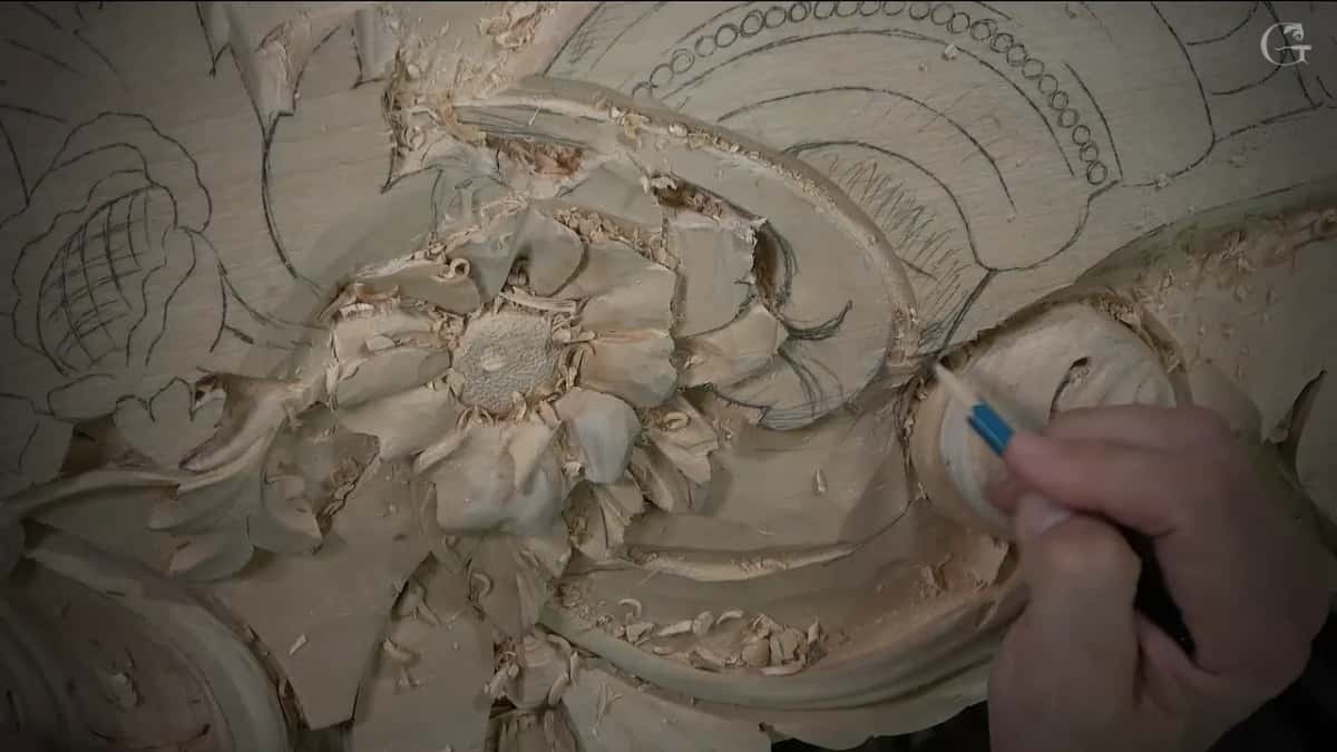 Marker in hand, riding along a scroll beside a finished flower with a dotted center