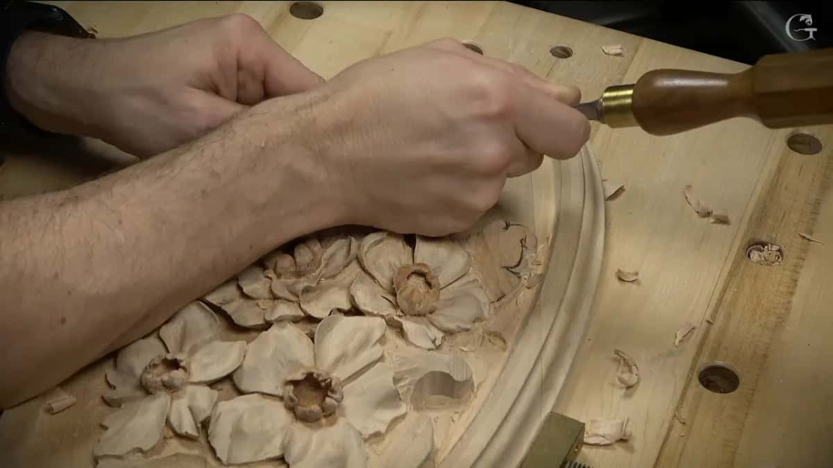 Seen from the other end of the bench, a long brown handle and a forearm reach over the leaf